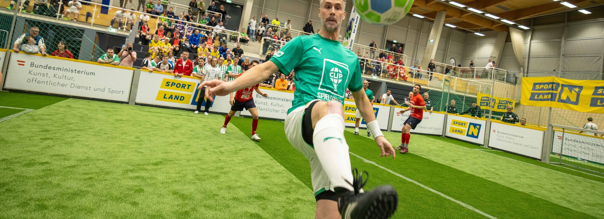 Mehrere Person am Fußballfeld, im Vordergrund nimmt Stefan Maierhofer den Ball aus der Luft an.