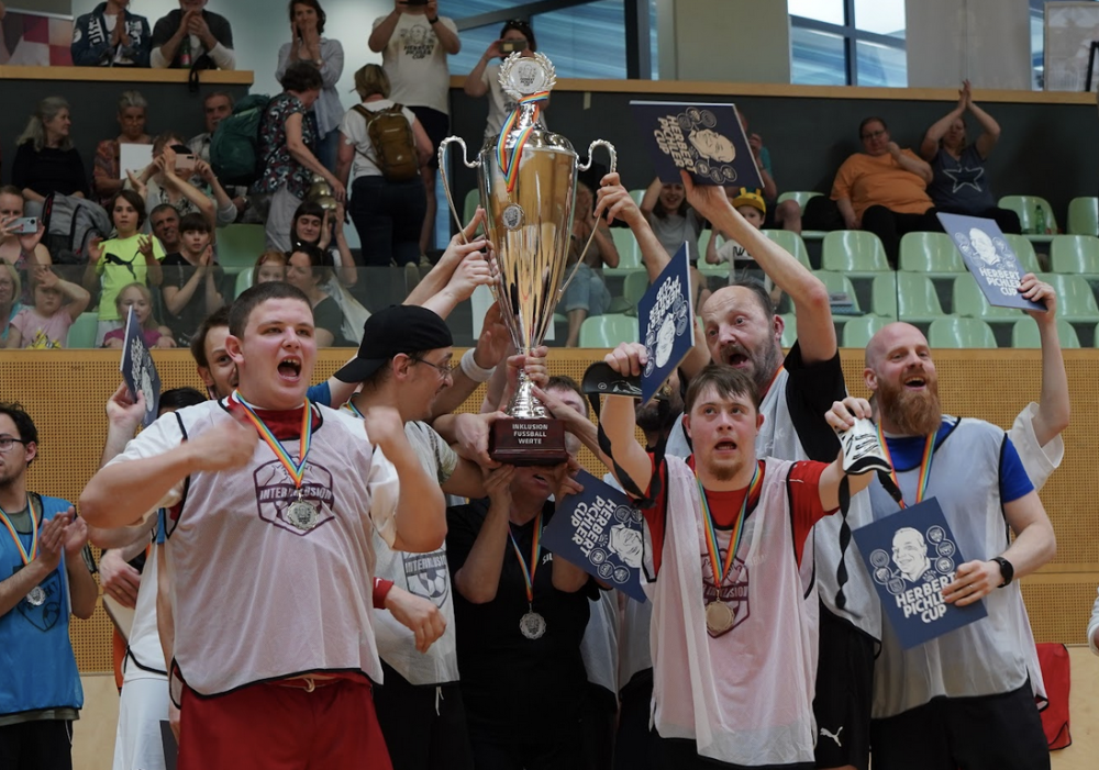 Mehrere Personen heben gemeinsam einen Pokal in die Höhe